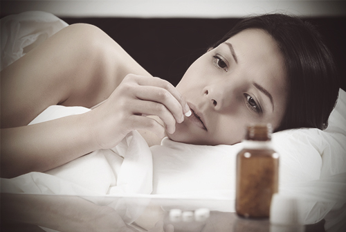 drugabuse_shutterstock-181337777-woman-in-bed-taking-pills-addict